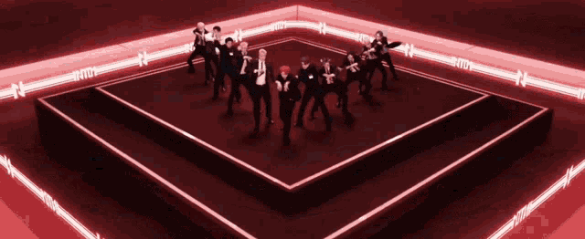 a group of people are standing on a stage with red lights