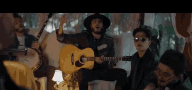 a man in a hat is playing an acoustic guitar in a group of men .