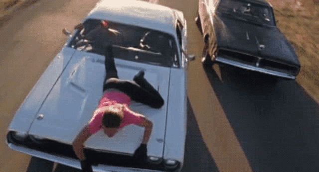 a man is laying on the hood of a white car .