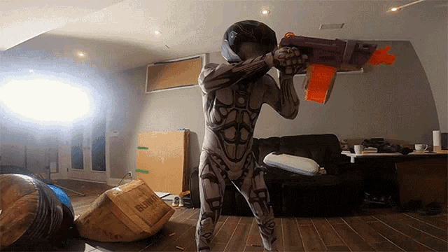 a man in a robot costume is holding a nerf gun in a living room