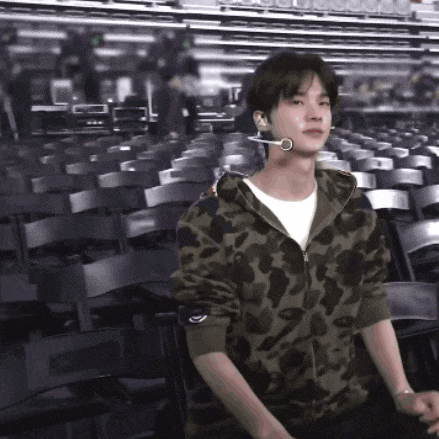 a man wearing a camo jacket is sitting in a stadium