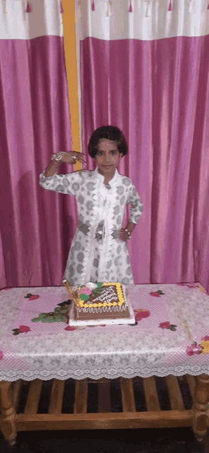 a little girl is standing in front of a birthday cake on a table