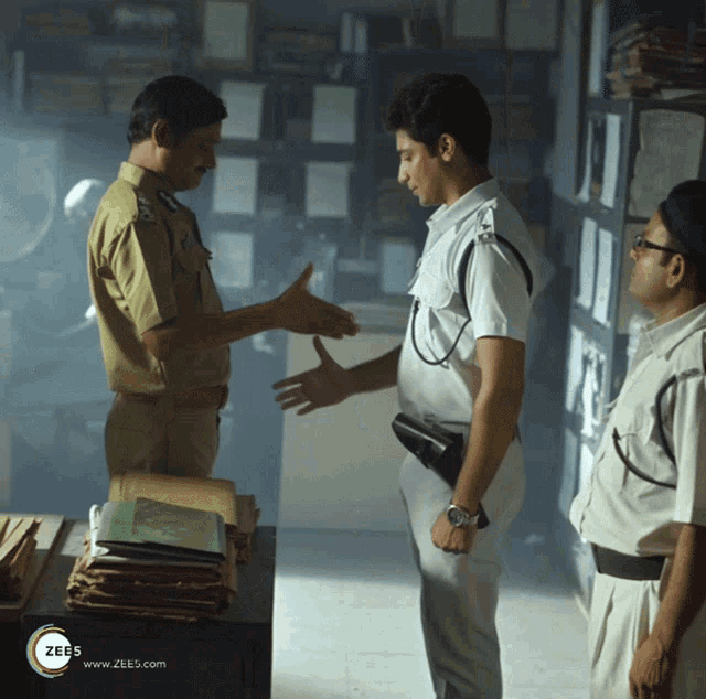 two police officers shaking hands in a dark room with a zees logo on the bottom left