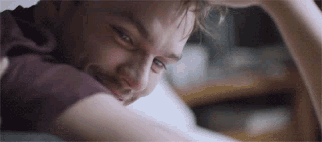 a man with a beard is laying on a bed with his head on his hand .