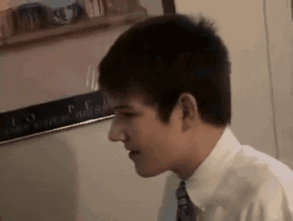 a young man in a white shirt and tie is looking at something .