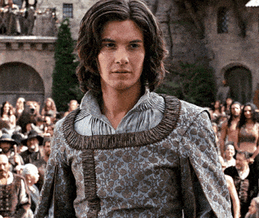 a man with long hair is wearing a blue and brown dress