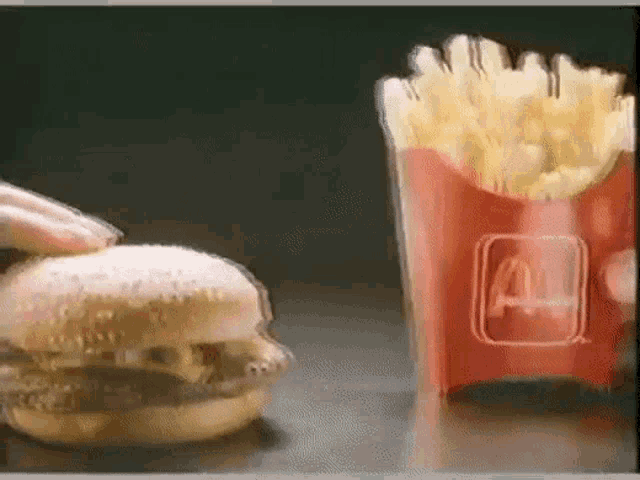a hamburger is being eaten next to a mcdonald 's french fries