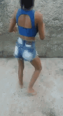 a woman in a blue crop top and shorts is dancing