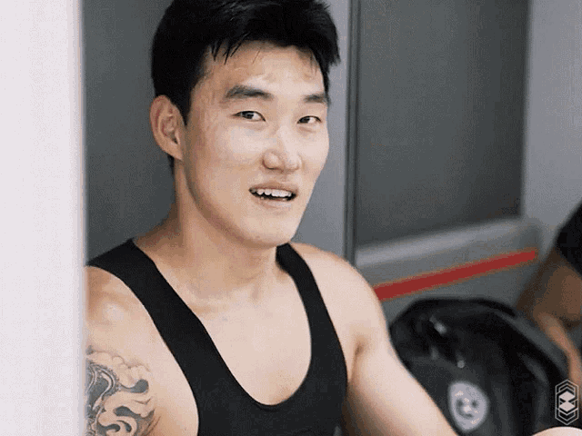 a man in a black tank top has a tattoo on his shoulder