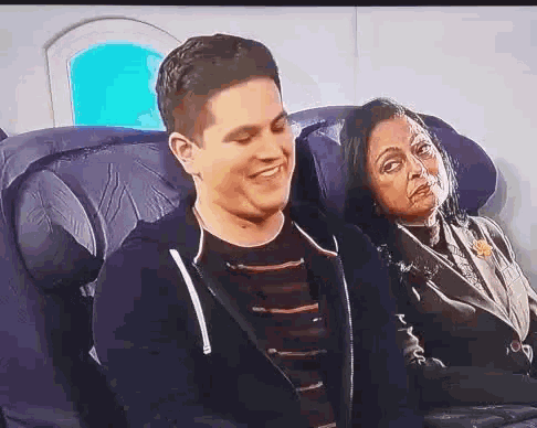 a man and woman are sitting on an airplane and the man is smiling