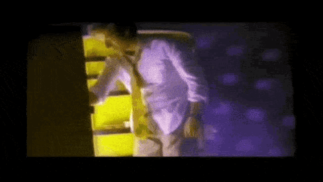 a man in a white shirt and tie is standing in front of a purple wall .