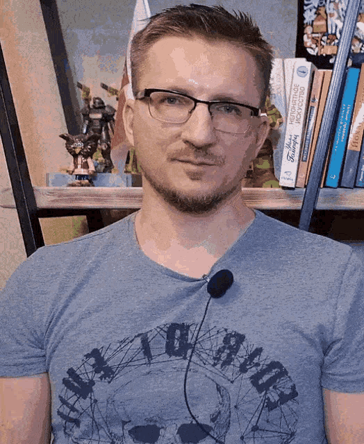 a man wearing glasses and a t-shirt with a skull on it is talking into a microphone