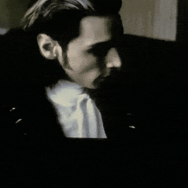 a man in a suit and tie is looking at something in the dark