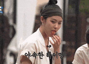 a woman wearing a headband is eating something with korean writing on her face