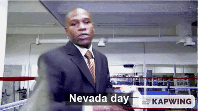 a man in a suit and tie is standing in a boxing ring and says nevada day