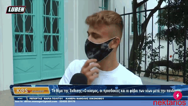 a man wearing a mask is talking into a microphone on a screen that says kos