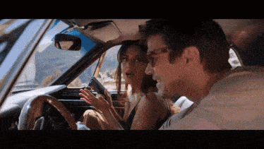 a man and a woman are sitting in a car with the woman holding a gun