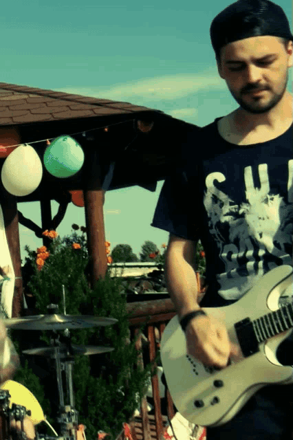 a man playing a guitar and wearing a shirt that says ' skull ' on it