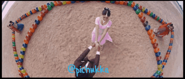 a woman in a pink dress is holding a man 's hand in a circle of colorful containers