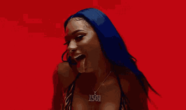 a woman with blue hair is wearing a bikini and a necklace with the word jesus on it .