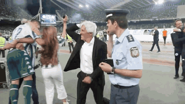 a man in a police uniform stands next to a group of people on a field
