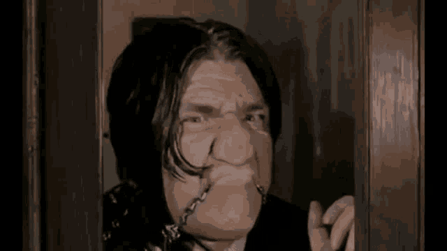 a man is making a funny face while looking out of a door .
