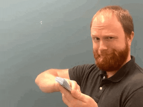a man with a beard is holding a bunch of cards in his hand