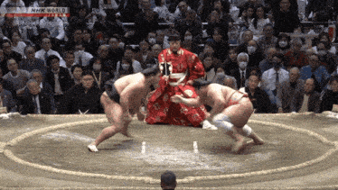 a sumo wrestler is fighting another wrestler in front of a crowd with nhk world on the bottom