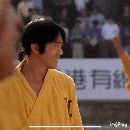 a man in a yellow kimono is smiling and looking at another man .