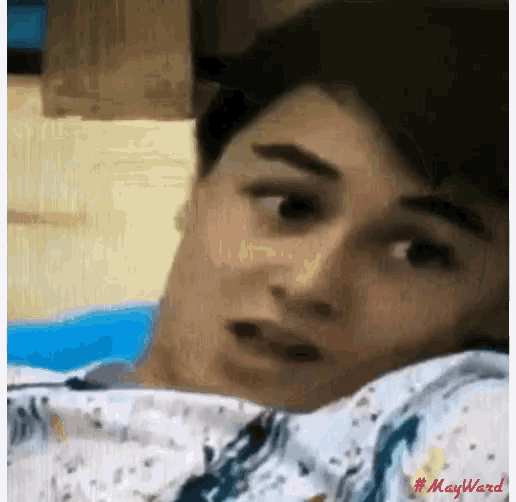 a young man is laying on a bed with his head on a pillow .