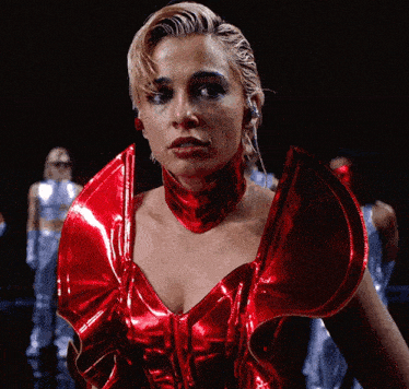 a woman is wearing a red metallic top and collar