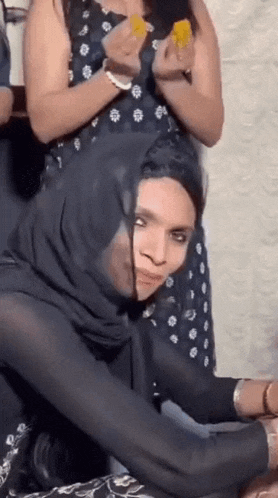 a woman in a hijab is sitting on a man 's lap and looking at the camera .