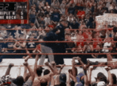 a crowd of people watching a wrestling match with a scoreboard that says 32 1 falls