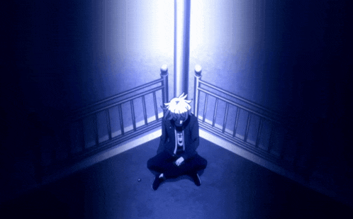 a person sitting in the corner of a room with a blue light shining on them