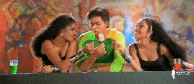 a man is eating an ice cream bar while two women look on .