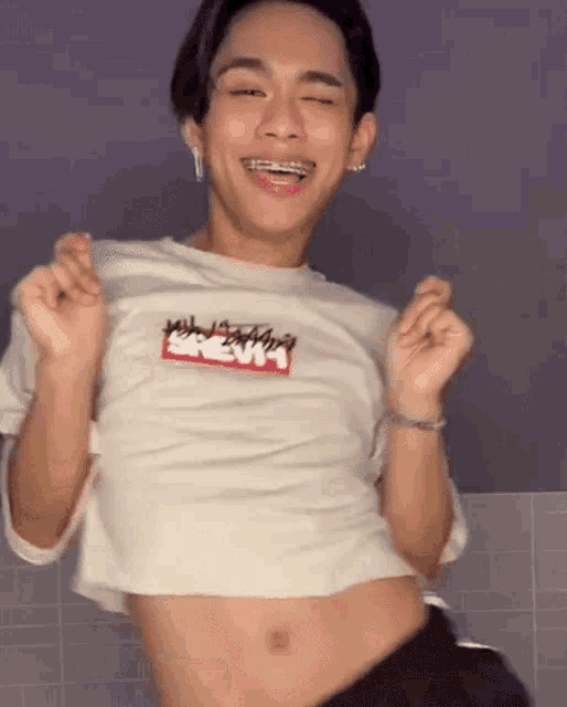 a young man wearing braces and a crop top is dancing .