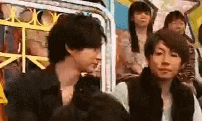 two men are standing next to each other in front of a crowd .
