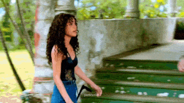a woman with curly hair is walking down a set of steps .