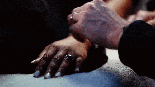 a man is holding a woman 's hand with a wedding ring on it .