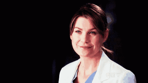 a close up of a woman wearing a white lab coat and a blue scrub top .