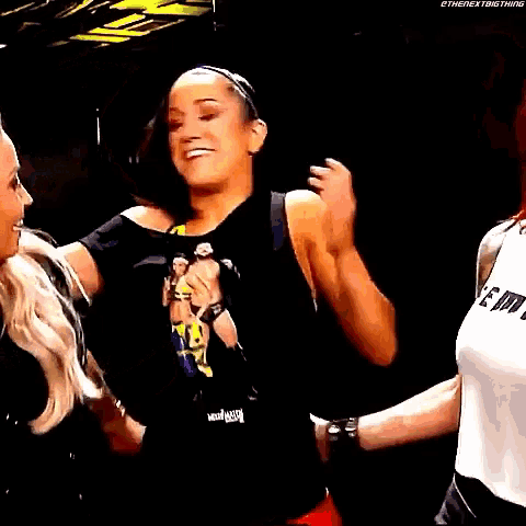two women are hugging each other and one is wearing a shirt that says feminist .