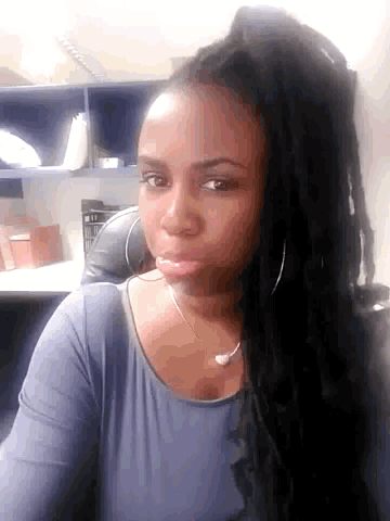 a woman with dreadlocks looks at the camera with a serious look on her face