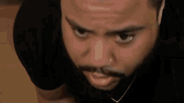 a man with a beard is wearing earbuds and looking at the camera