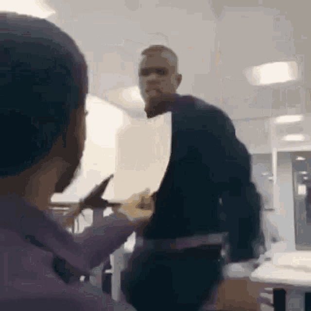 a man is holding a piece of paper in his hand while another man holds a piece of paper .