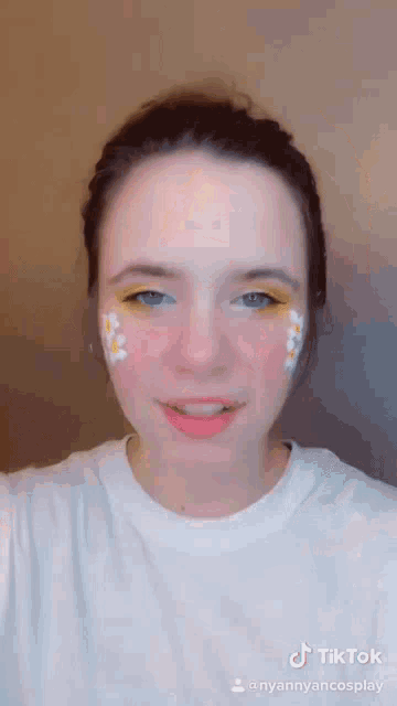 a woman with flowers painted on her face is wearing a white t-shirt