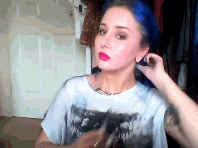a woman with blue hair is wearing a t-shirt with a picture of a zombie on it