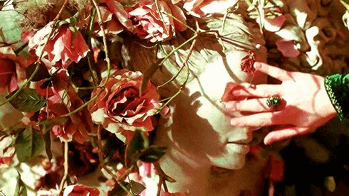 a woman 's hand is touching a statue of a woman with roses on her head .