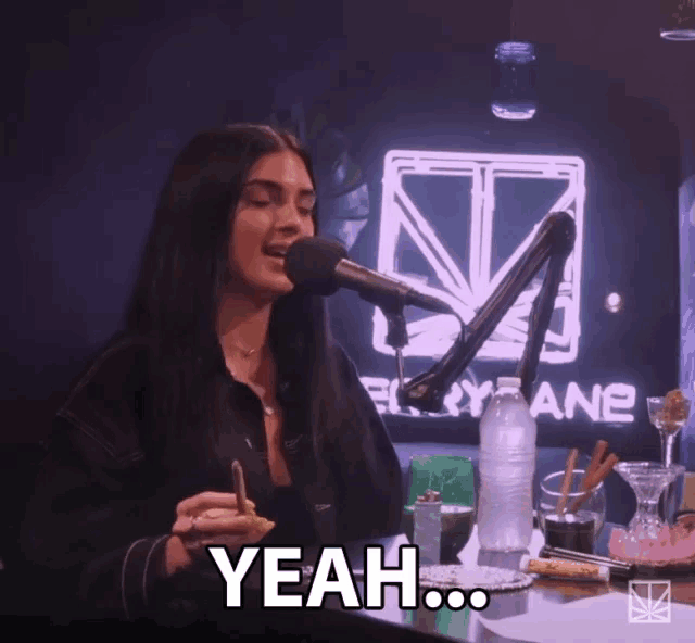 a woman is sitting in front of a microphone and says " yeah "