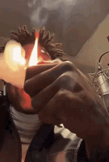 a close up of a person lighting a cigarette with a microphone in the background
