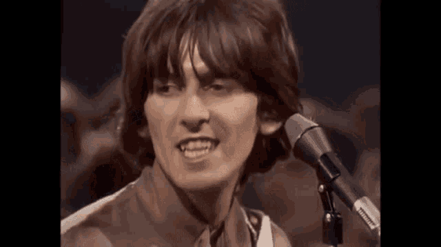 a close up of a man singing into a microphone .